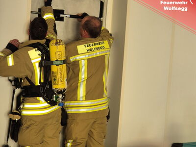 Zwei Feuerwehrmänner errichten eine Rauchsperre in einem Türdurchgang