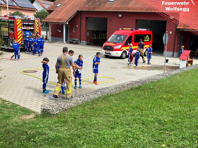 Kinder im Fußballdress spritzen Wasser mit einem Schlauch