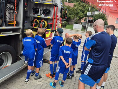 Kinder im Fußballdress begutachten die Geräte im Feuerwehrauto