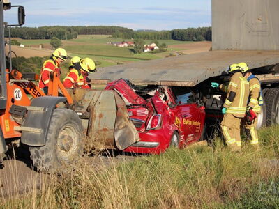 Feuerwehraktive wollen ein zwischen Lader und LKW eingeklemmtes Auto bergen