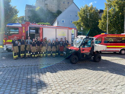 Aktive der FF Wolfsegg vor dem HLF10 auf dem Dorfplatz