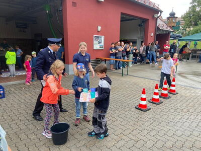 Ein Kind balanciert mit Wasser gefüllte Becher auf einem Tablett