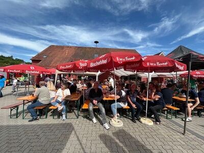 Besucher sitzen unter den Sonnenschirmen