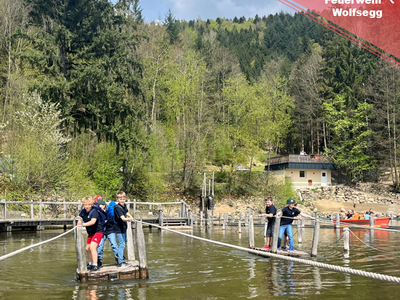 Kinder ziehen sich auf einem Floß über einen See